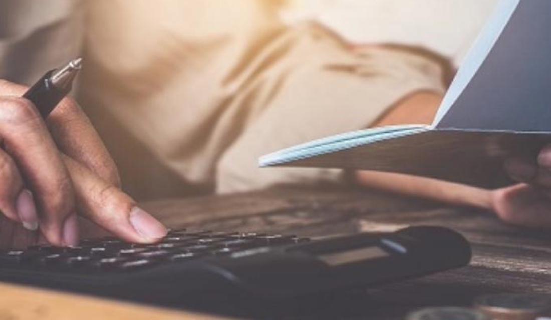 Person tippt in einem Taschenrechner