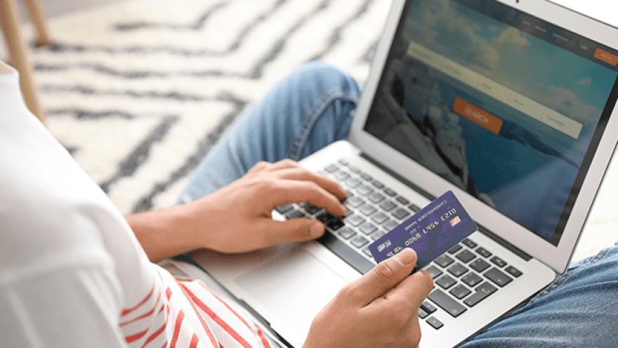 Person bucht mit Laptop und Kreditkarte Flugtickets