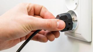 Hand hält Stecker an eine Steckdose