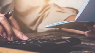 Person tippt in einem Taschenrechner